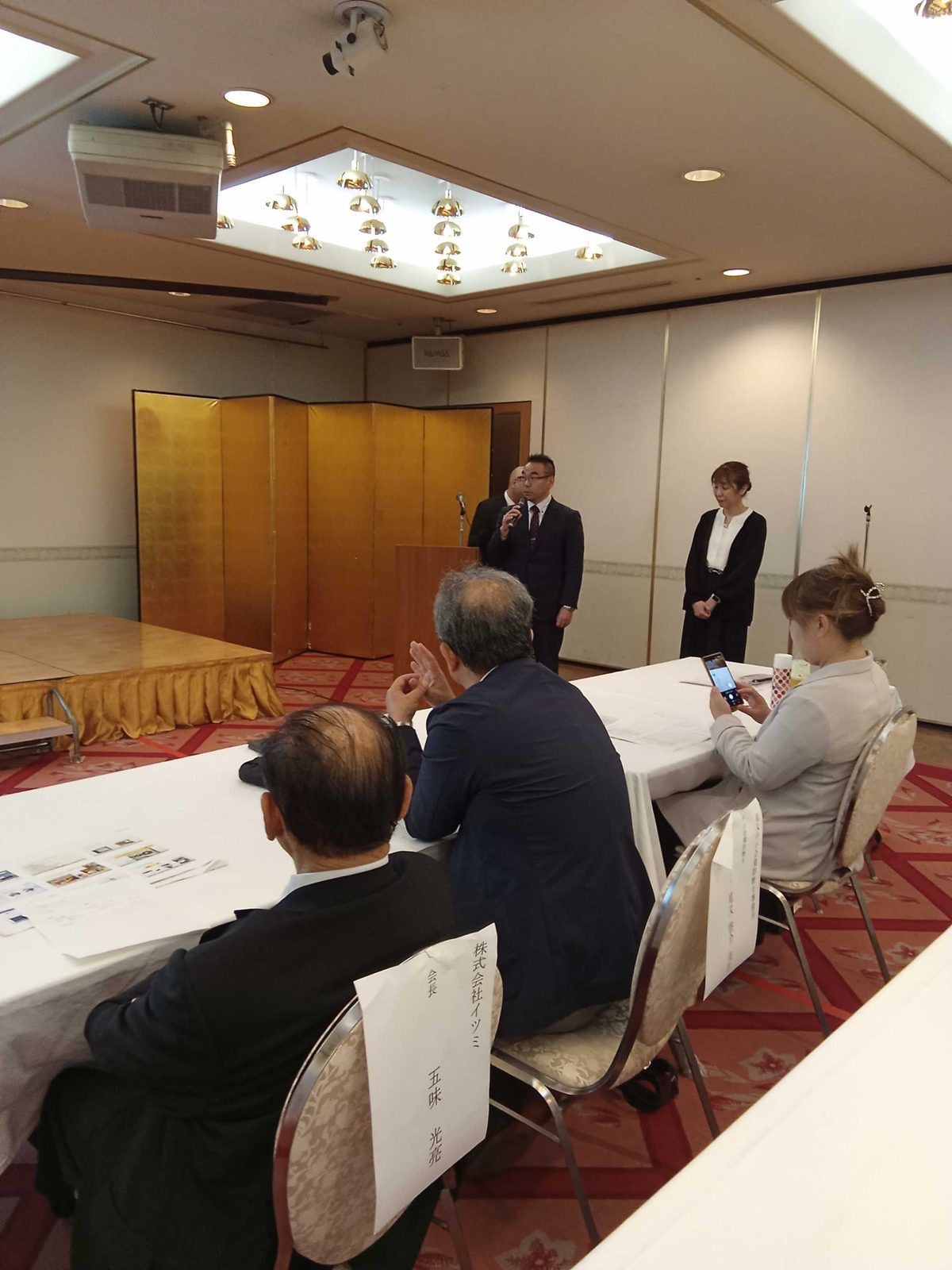 発表会でマイクを持ってあいさつする社員